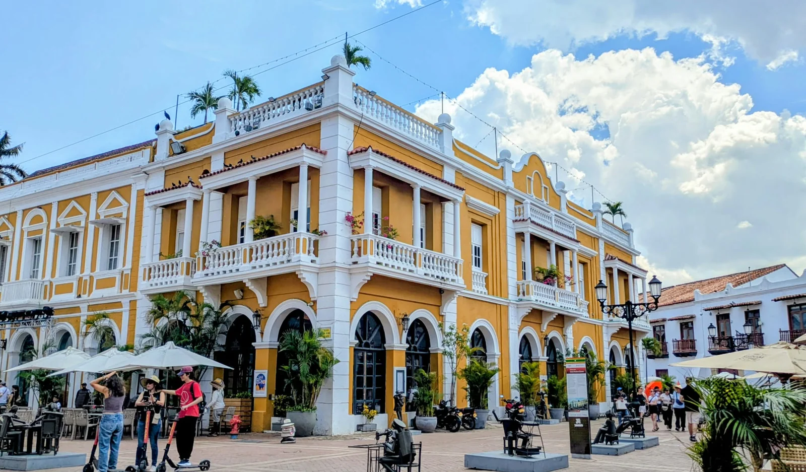 Edificio amarillo con balcones blancos en una plaza de Cartagena de Indias.
