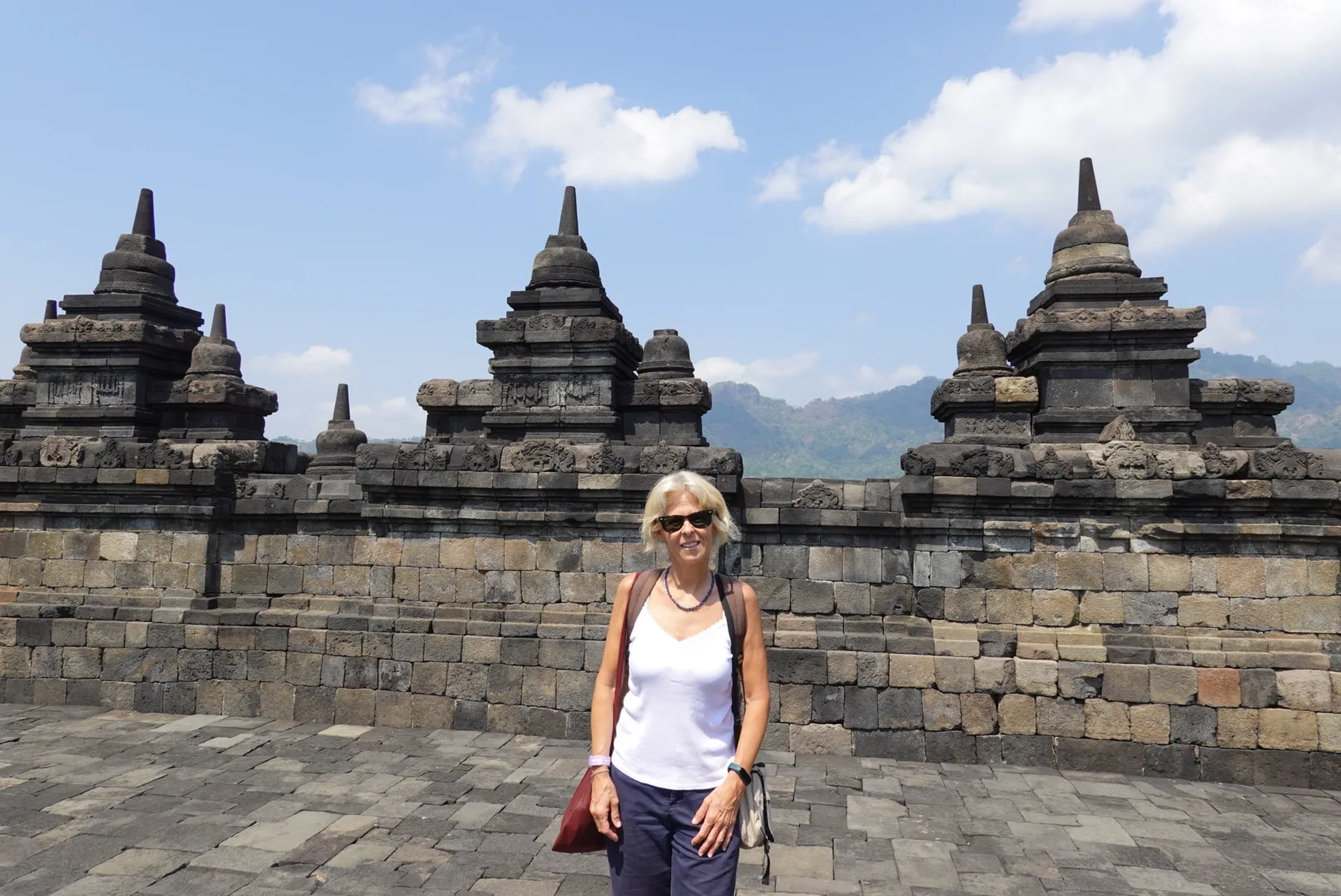 Gloria recorre las estupas de piedra del templo de Borobudur bajo un cielo azul.