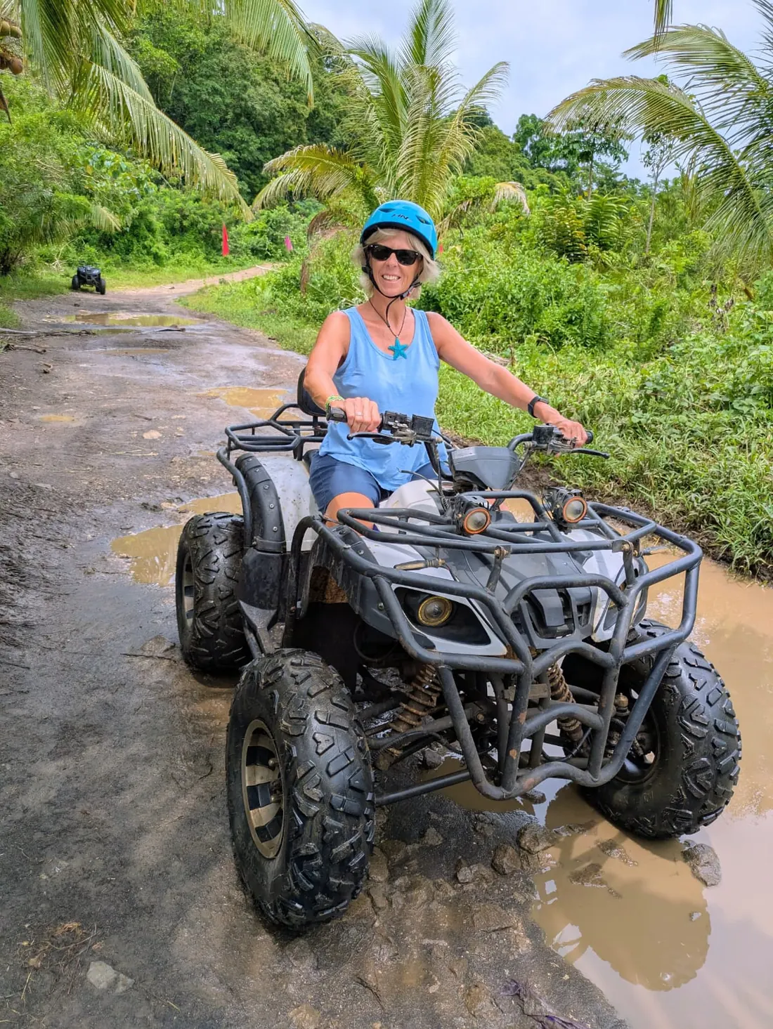 Gloria conduce un quad por un camino rodeado de vegetación tropical