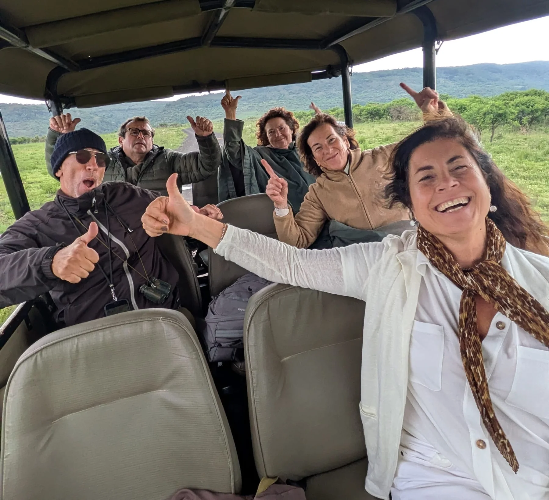 Grupo de viajeros sonriendo en un vehículo de safari abierto